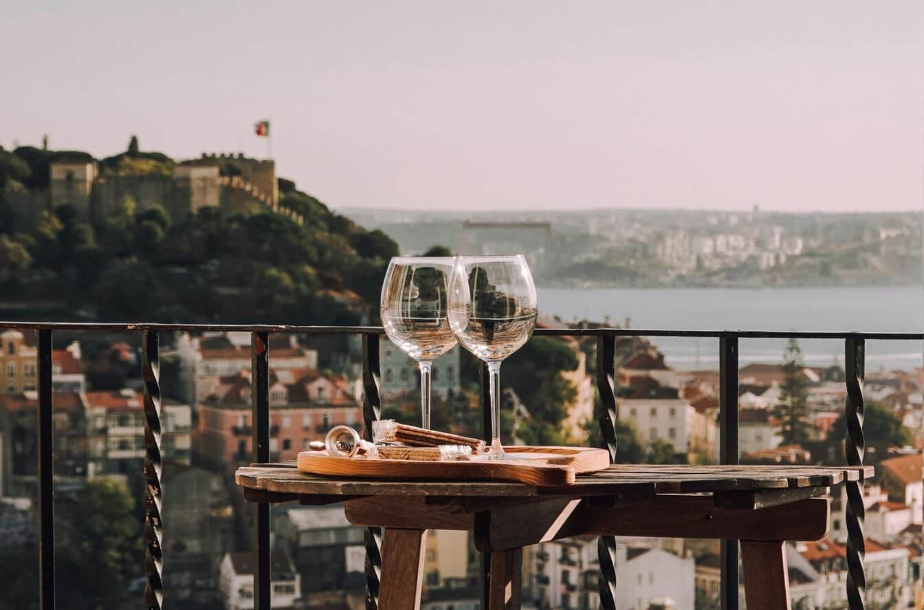 uitzicht vanaf een balkon met een glas wijn over een Portugeese stad