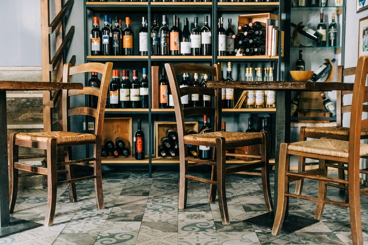 Wijnbar met houten tafeltjes en rekken met flessen wijn op de achtergrond
